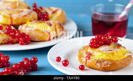 Pasta sfoglia con budino e ribes rosso sul blu di un tavolo di legno. Torta alla frutta. Foto Stock