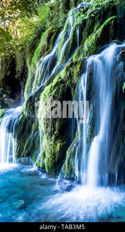 Bella cascata streaming verso il basso un fresco verde collina nell'acqua turqouise dei laghi entro il parco nazionale di Plitvice Foto Stock