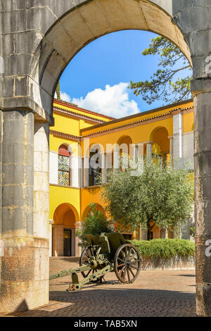 GARDONE RIVIERA, Italia - Settembre 2018: arco di pietra con il vecchio campo di pistola in il Vittoriale degli Italiani giardini in Gardone Riviera. Foto Stock