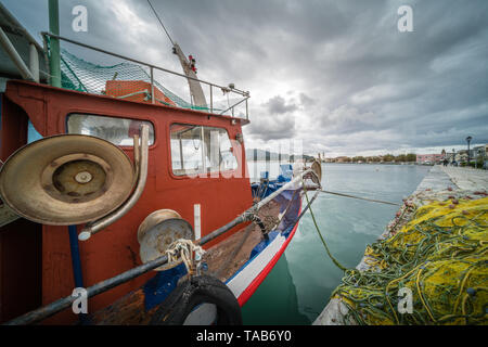 Zakynthos Greece - Aprile 2019 : pile di grandi dimensioni delle maglie delle reti e i pescatori barca ormeggiata sulla riva nel porto di Zante, ISOLE IONIE Foto Stock