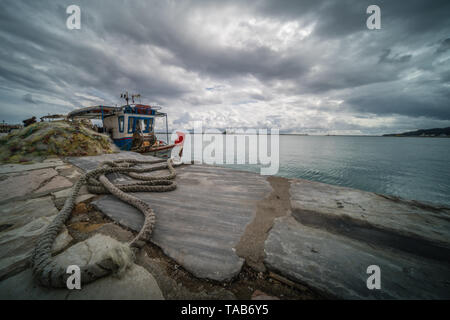 Zakynthos Greece - Aprile 2019 : pile di grandi dimensioni delle maglie delle reti e i pescatori barca ormeggiata sulla riva nel porto di Zante, ISOLE IONIE Foto Stock