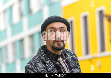 Ritratto di un elegante bel giovane con un rivestimento esterno. Un grave uomo che indossa un cappotto e una maglietta guardando fiduciosi alla fotocamera. Foto Stock
