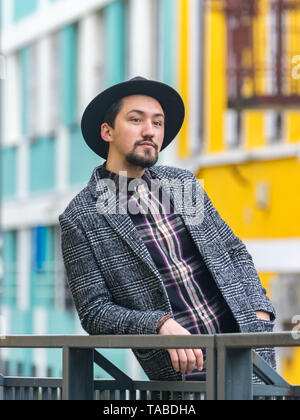 Ritratto di un elegante bel giovane con un rivestimento esterno. Un uomo che indossa un cappotto e una camicia che guarda lontano e pensando a. Foto Stock