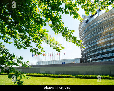 Tranquillo e pacifico di visualizzazione ampia facciata del Parlamento europeo vista attraverso gli alberi della sede di Strasburgo un giorno prima del 2019 sulle elezioni per il Parlamento europeo - cielo blu chiaro Foto Stock