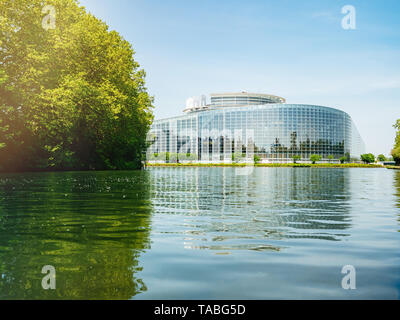 Basso angolo di visualizzazione ampia facciata del Parlamento europeo in sede di Strasburgo un giorno prima del 2019 sulle elezioni per il Parlamento europeo - cielo blu chiaro e tranquillo fiume Ill acqua luce solare flare. Foto Stock