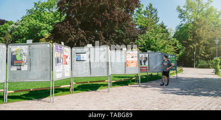 Strasburgo, Francia - 23 Maggio 2019: poster nel verde parco di sole per 2019 sulle elezioni per il Parlamento europeo con i politici francesi e maschio di runner guardando i candidati Foto Stock