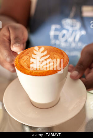 Tazza di cappuccino rosso (realizzata con rooibos tea) in quattro venti & Cafe a Cape Town. Il tè è distintivo di colore rosso è chiaramente visibile. Foto Stock