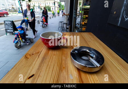 Bucarest, Romania - 18 Maggio 2019: un posacenere pieno di fumava sigarette su un tavolo di fronte a un coffee shop in Bucarest. Leggi europee vietano smok Foto Stock