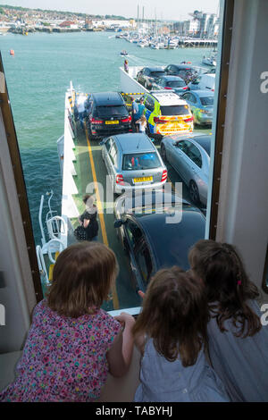 Bambino / Kids / passeggeri su un imbuto rosso traghetto tra terraferma britannica - Southampton - & Cowes sull'Isola di Wight guardare fuori dalla finestra e verso il basso sul ponte garage. Regno Unito. (99) Foto Stock