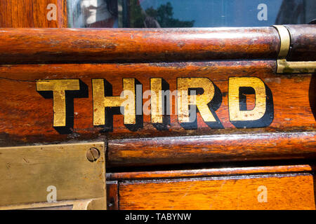 La terza parola (classe) dipinta in oro / lettere scritte sul slam porta con la cattura di un vecchio vintage treno a vapore carrello. England Regno Unito. (99) Foto Stock