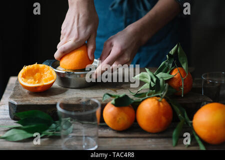 Giovane uomo con le mani in mano la spremitura di Orange Foto Stock