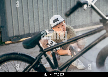 Ragazzo di lavaggio bici bmx con la rondella di pressione sul cantiere Foto Stock