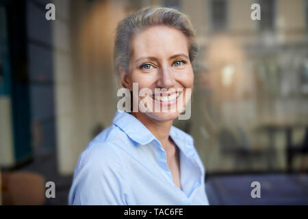 Ritratto di donna sorridente dietro il vetro di finestra Foto Stock