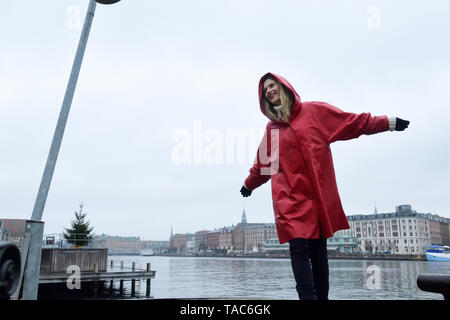 Danimarca, Copenaghen, donna felice al waterfront in condizioni di tempo piovoso Foto Stock