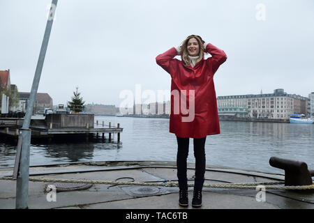 Danimarca, Copenaghen, donna felice al waterfront in condizioni di tempo piovoso Foto Stock