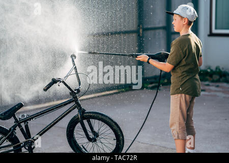 Ragazzo di lavaggio bici bmx con la rondella di pressione sul cantiere Foto Stock