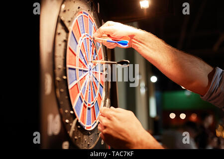 Close-up di uomo prendendo le freccette da electronic dartboard Foto Stock