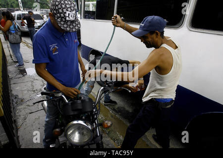 Guacara, Carabobo, Venezuela. 23 Maggio, 2019. Il 23 maggio 2019. Un trasporto pubblico driverÂ"s e il suo aiutante prendere la benzina da un motocicle per il suo bus veicolo in modo pubblico, nella città di Guacara, Carabobo stato. Foto: Juan Carlos Hernandezz Credito: Juan Carlos Hernandez/ZUMA filo/Alamy Live News Foto Stock