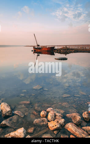 Vista panoramica del lago e la vecchia barca al tramonto di un giorno di estate Foto Stock