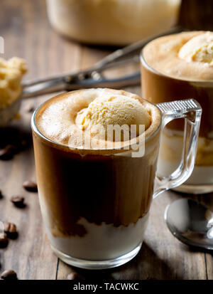 Caffè ghiacciato con gelato alla vaniglia chiamato affogato in Italia su una tavola in legno rustico Foto Stock