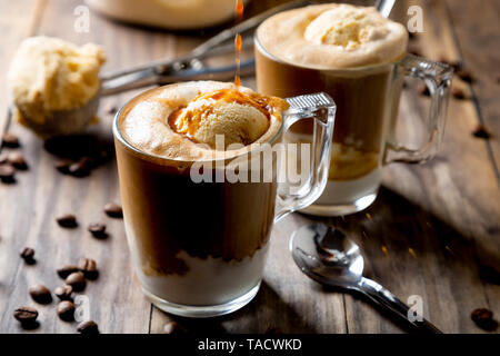 Versare il caffè sul gelato alla vaniglia per fare un caffè affogato su una tavola in legno rustico Foto Stock
