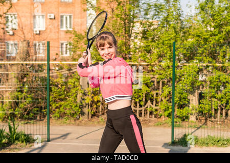 Ritratto di una bella donna sorridente giocando a tennis oscillazione un racket Foto Stock