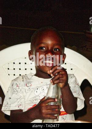 Timbuctu, MALI - febbraio circa, 2019. Unidentified bambino povero sta bevendo una coca-cola bottiglia, data dal turista nella strada del villaggio in Mali Foto Stock