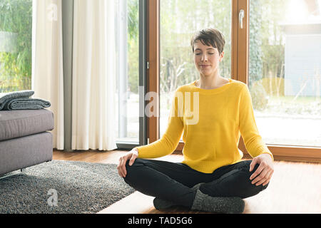 Ritratto di donna seduta sul pavimento della sala di meditazione Foto Stock