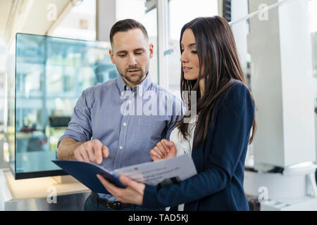 Imprenditore e imprenditrice guardando cartella nel moderno stabilimento Foto Stock