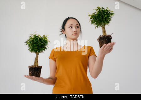 Giovane donna con due alberi di bonsai Foto Stock