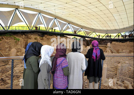 Un gruppo di donne musulmane indagine la vista degli scavi archeologici di un antico in pietra sito cerimoniale a Gobekli Tepe in Sanliurfa, Turchia Foto Stock