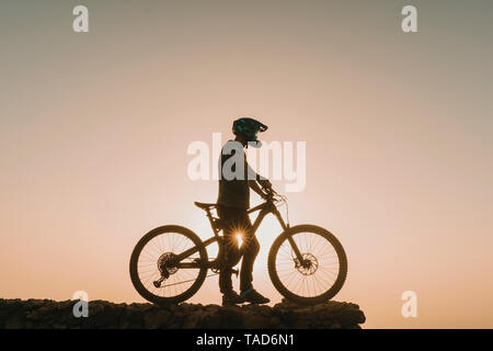 Spagna, Lanzarote, mountainbiker su un viaggio al tramonto Foto Stock