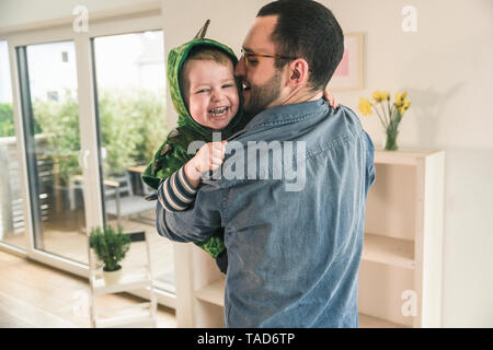 Padre giocando con il figlio felice in un costume a casa Foto Stock