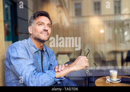 Ritratto di uomo dietro il vetro di finestra in un cafe Foto Stock