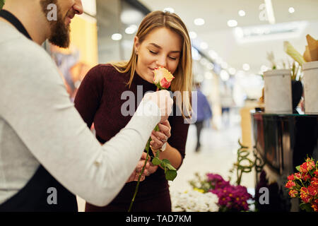 Fioraio lasciando che il cliente odore in fiore nel negozio di fiori Foto Stock