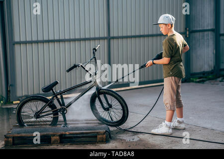 Ragazzo di lavaggio bici bmx con la rondella di pressione sul cantiere Foto Stock