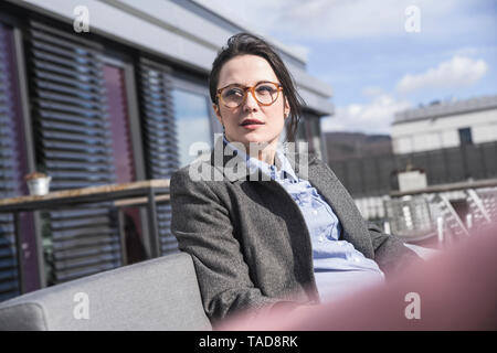 Imprenditrice seduti sulla terrazza sul tetto guardando intorno Foto Stock