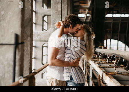 Coppia giovane baciare in una vecchia stazione ferroviaria Foto Stock