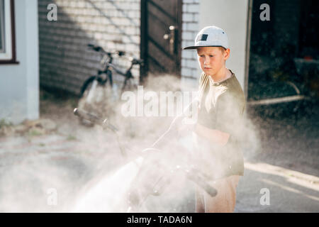 Ragazzo di lavaggio bici bmx con la rondella di pressione sul cantiere Foto Stock