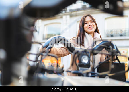 Spagna, Madrid, sorridente giovane donna con noleggio bici in città Foto Stock