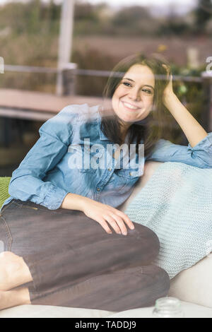 Ritratto di donna felice dietro il vetro di finestra a casa Foto Stock