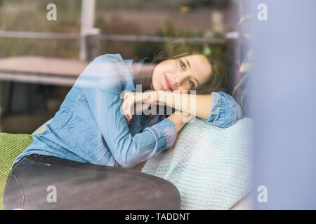 Ritratto di una donna dietro il vetro di finestra a casa Foto Stock