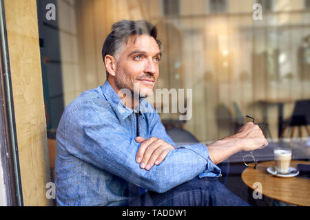 Ritratto di uomo dietro il vetro di finestra in un cafe Foto Stock