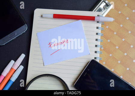 Esempio scritto su carta isolato sulla tavola nera Foto Stock