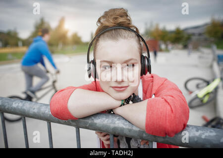 Ritratto di ragazza adolescente che indossano le cuffie a uno skatepark Foto Stock