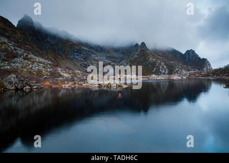 Norvegia Isole Lofoten Henningsvaer, uomo in piedi alla riva del mare con i bracci sollevati Foto Stock