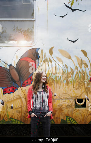 Sorridente ragazza adolescente in piedi in un dipinto di carrozza del treno Foto Stock