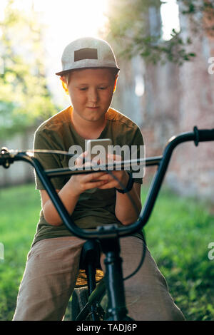 Ragazzo con la bmx bike tramite telefono cellulare Foto Stock