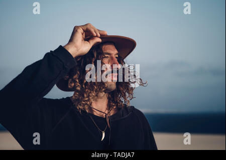 Giovane uomo con il cappello e i baffi nelle dune Foto Stock