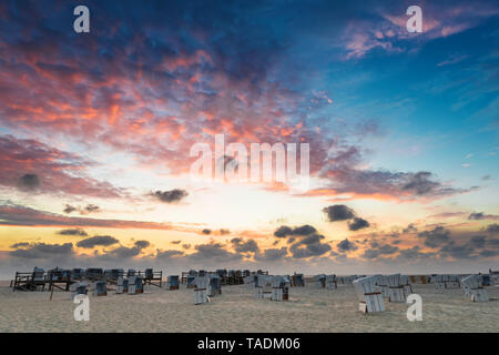 Germania, Sankt Peter Ording, incappucciati sedie a sdraio sulla spiaggia in sunset Foto Stock